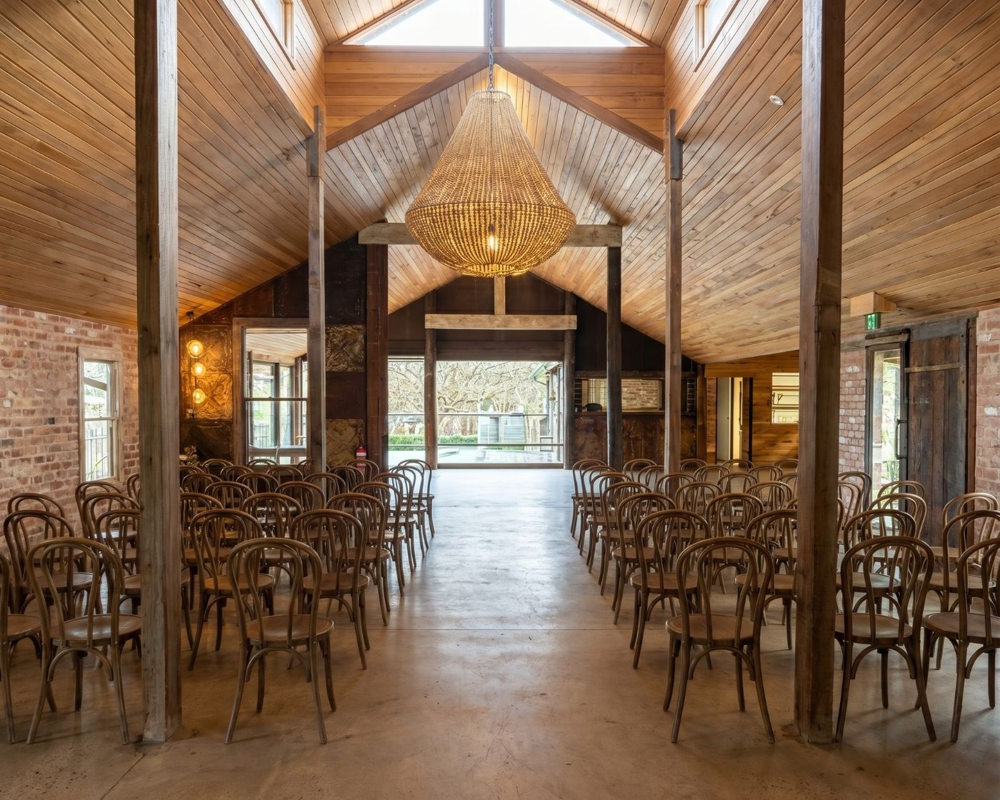 Rustic winery room with high timber ceiling, set with rows of chairs for a service