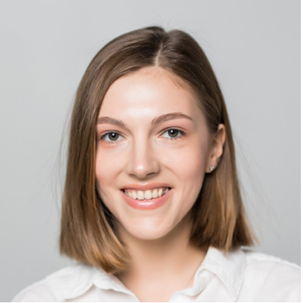 Smiling young woman with shoulder-length brown hair wearing a white shirt against a gray background.