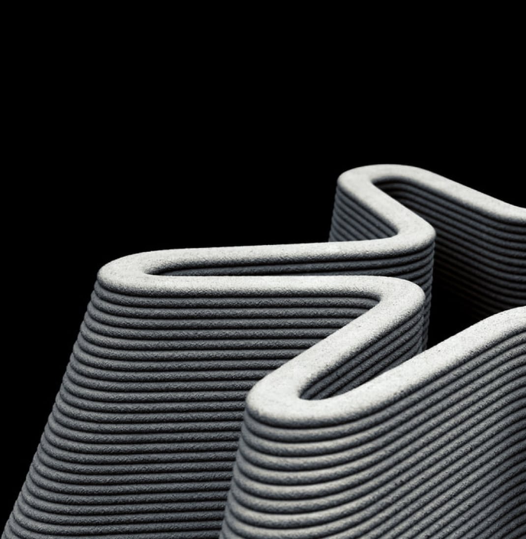 Close-up of a gray, layered 3D-printed object with a wavy, hollow structure on black background.