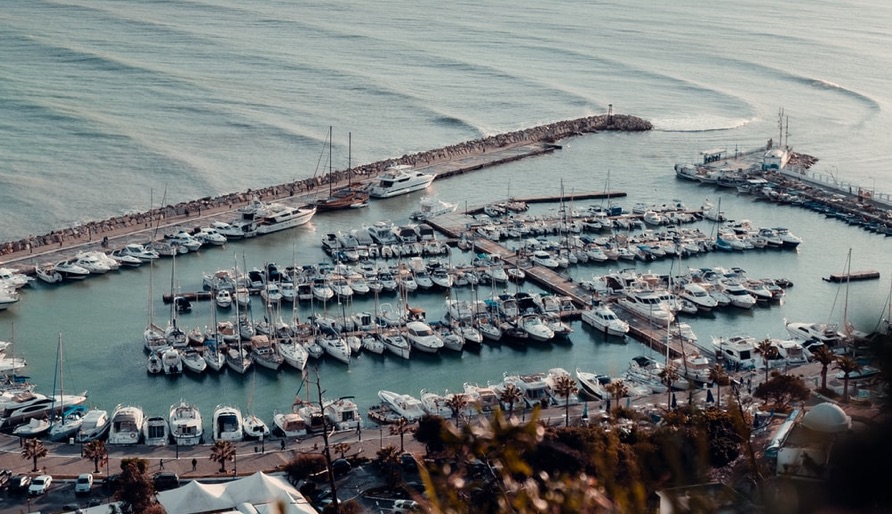 Aerial view of a marina with numerous docked boats and yachts on calm sea water.