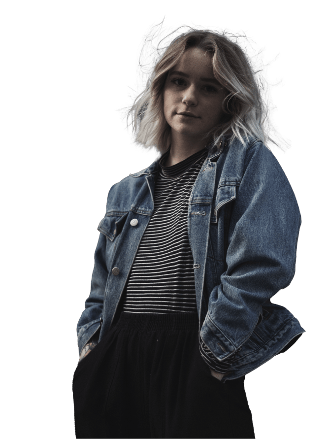Young woman with blonde hair wearing a denim jacket and striped shirt looking at the camera.