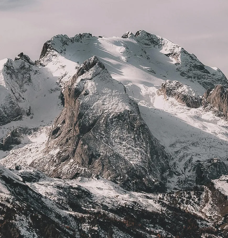 Snow-covered rugged mountain peaks under a cloudy sky.