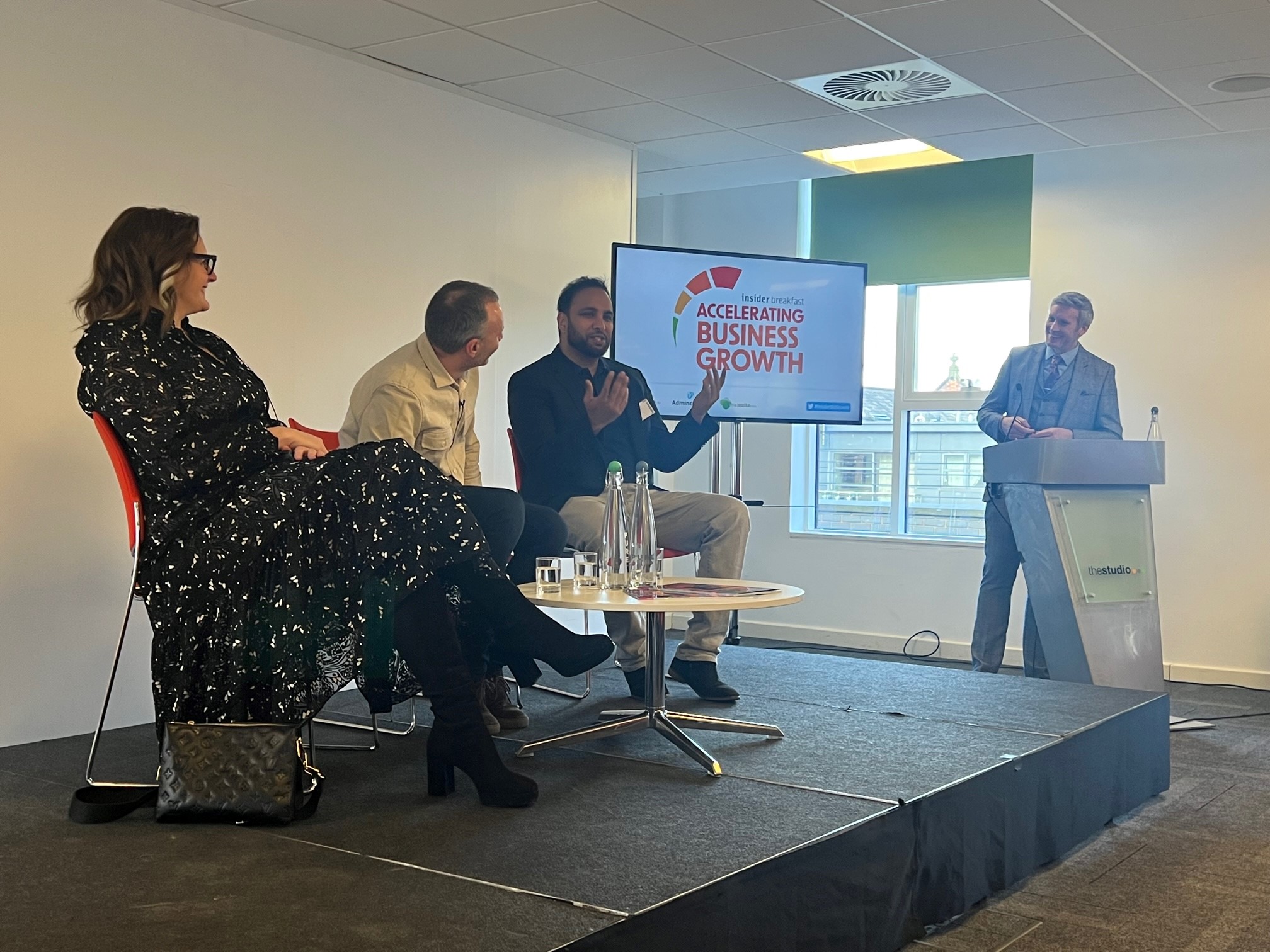 Panel discussion at a Hakim Group event with speakers presenting on stage to an audience.