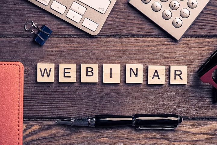 Webinar promotional graphic with the word "WEBINAR" spelled out on letter tiles on a desk with office supplies.