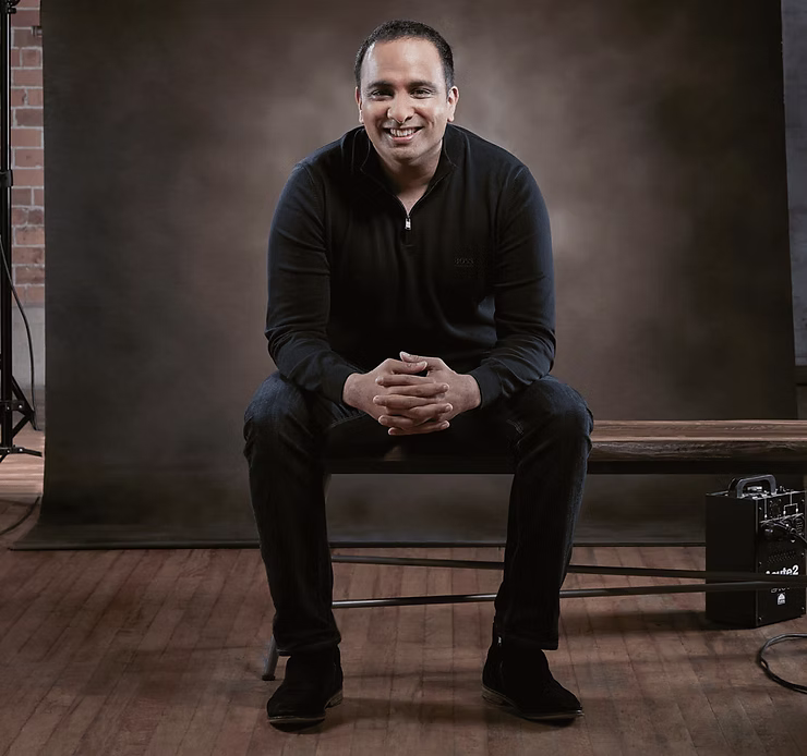Portrait of Imran Hakim seated in a photography studio with a relaxed pose.