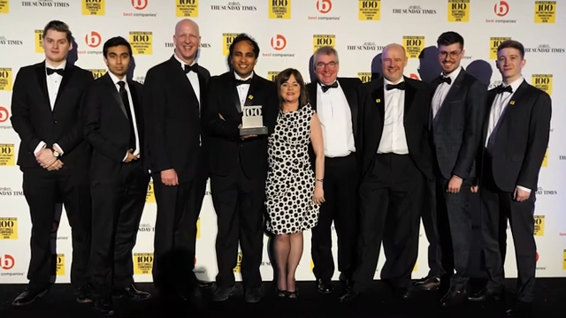 Imran Hakim and colleagues posing at a business awards ceremony with an award trophy.