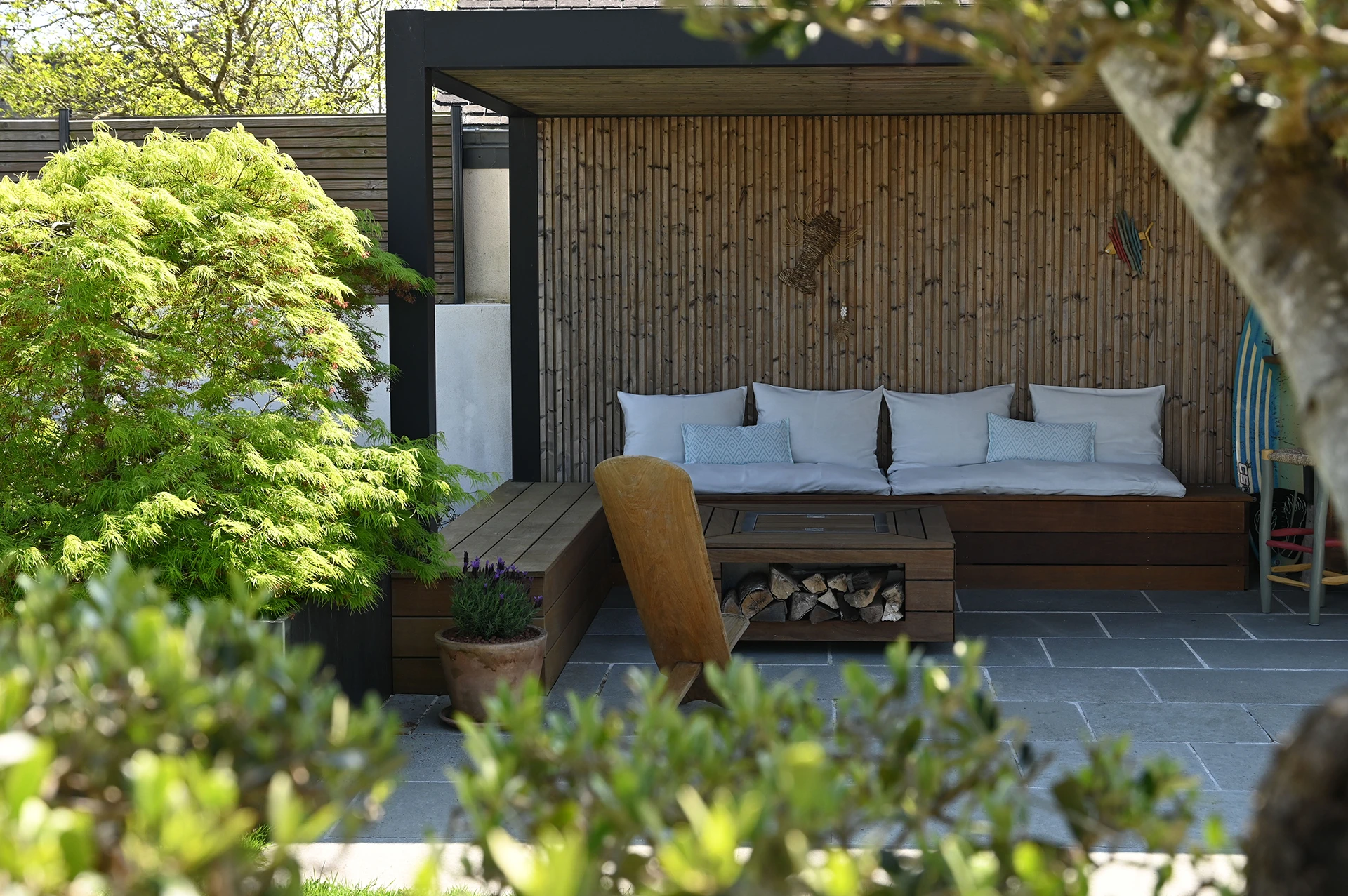 Pergola Maluwi en aluminium et bois dans un jardin à Plouhinec, entourée de massifs végétalisés et d’une terrasse en pierre naturelle.