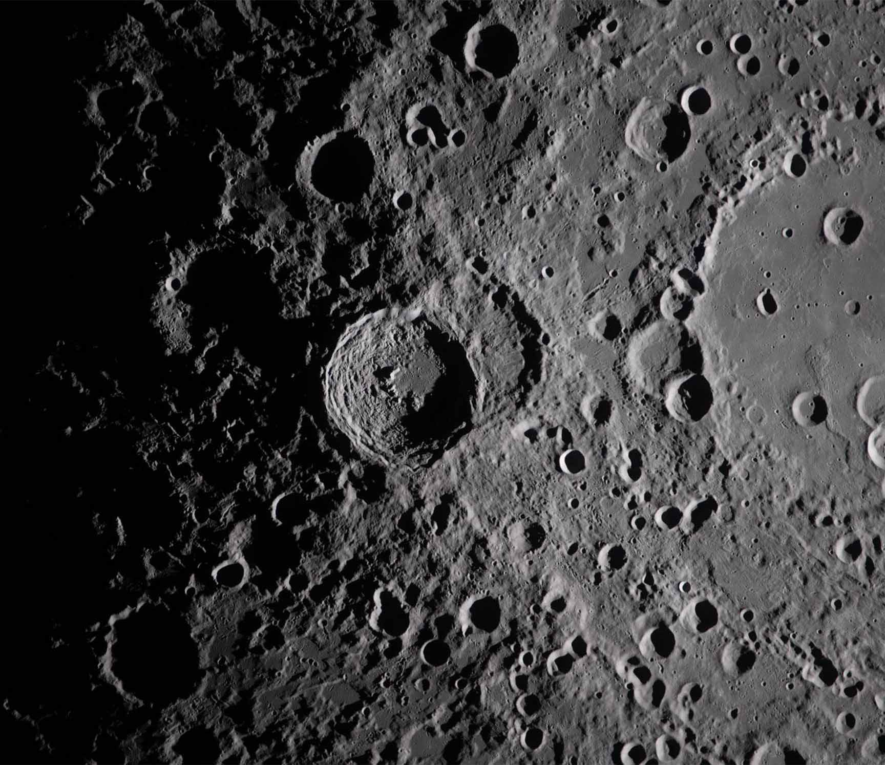 Kuun pinnan yksityiskohtainen harmaasävyinen kuva, jossa näkyy lukuisia kraattereita eri kokoisina.