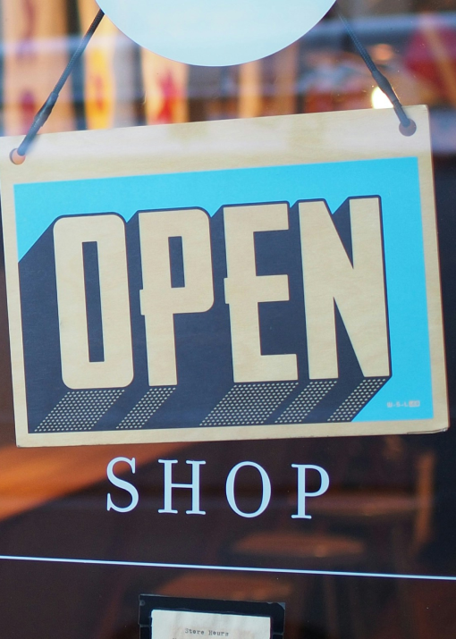 Picture of a card in front of a door of a shop showing the shop is ope for business.