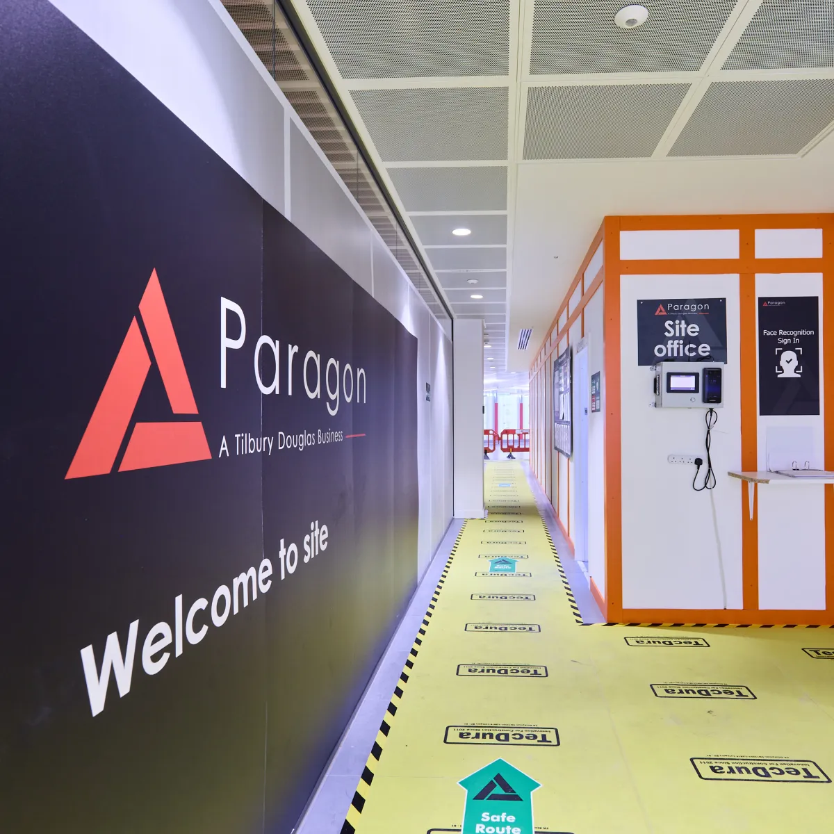 Paragon welcome sign beside a temporary corridor with yellow protective flooring.
