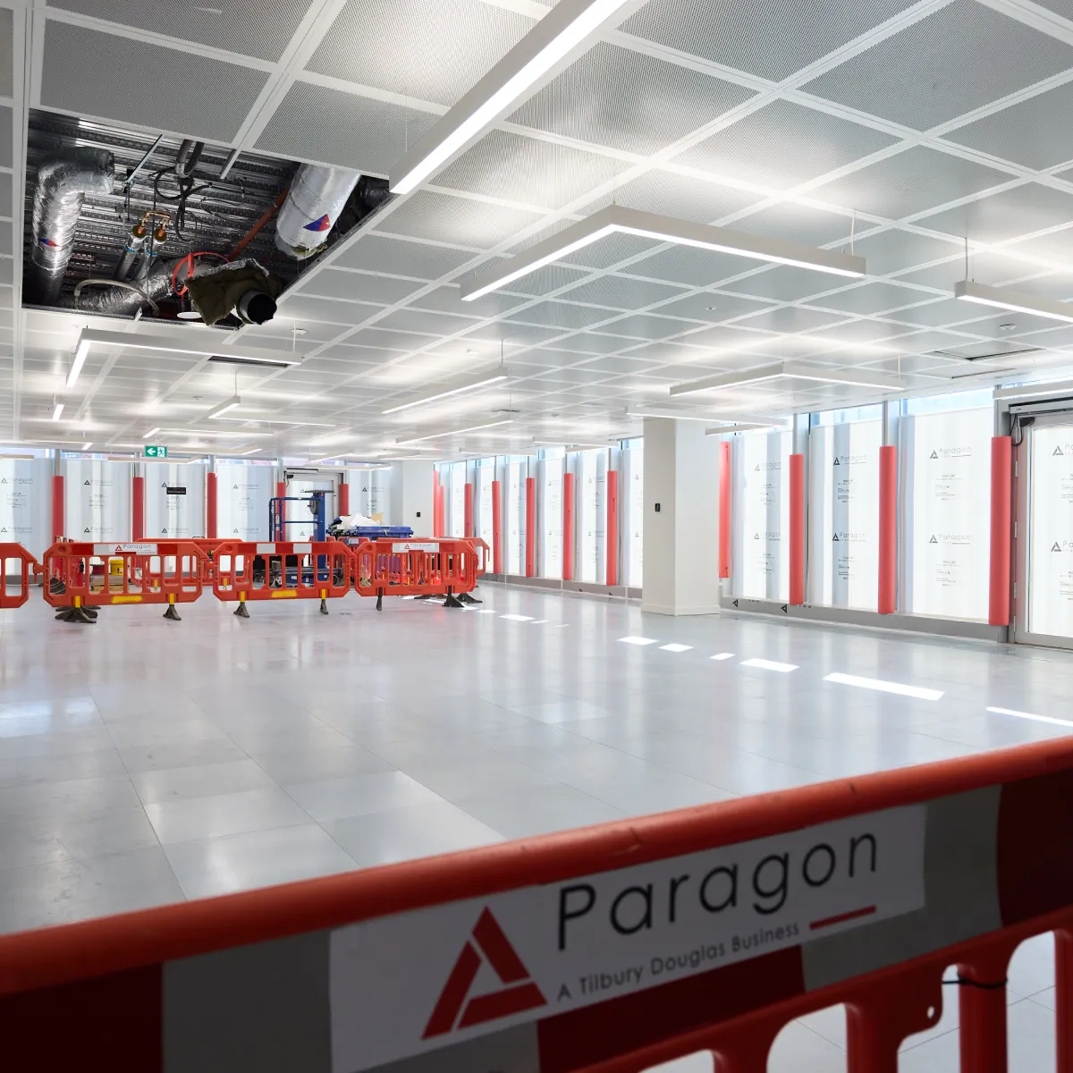 Large open interior under construction with orange safety barriers in the foreground.