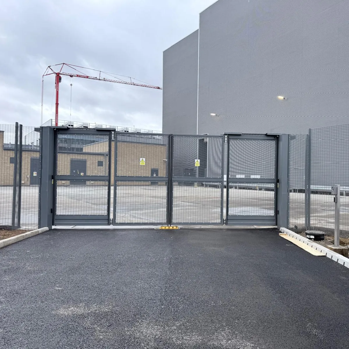 Secure outdoor site area with fencing beside a grey modular building.
