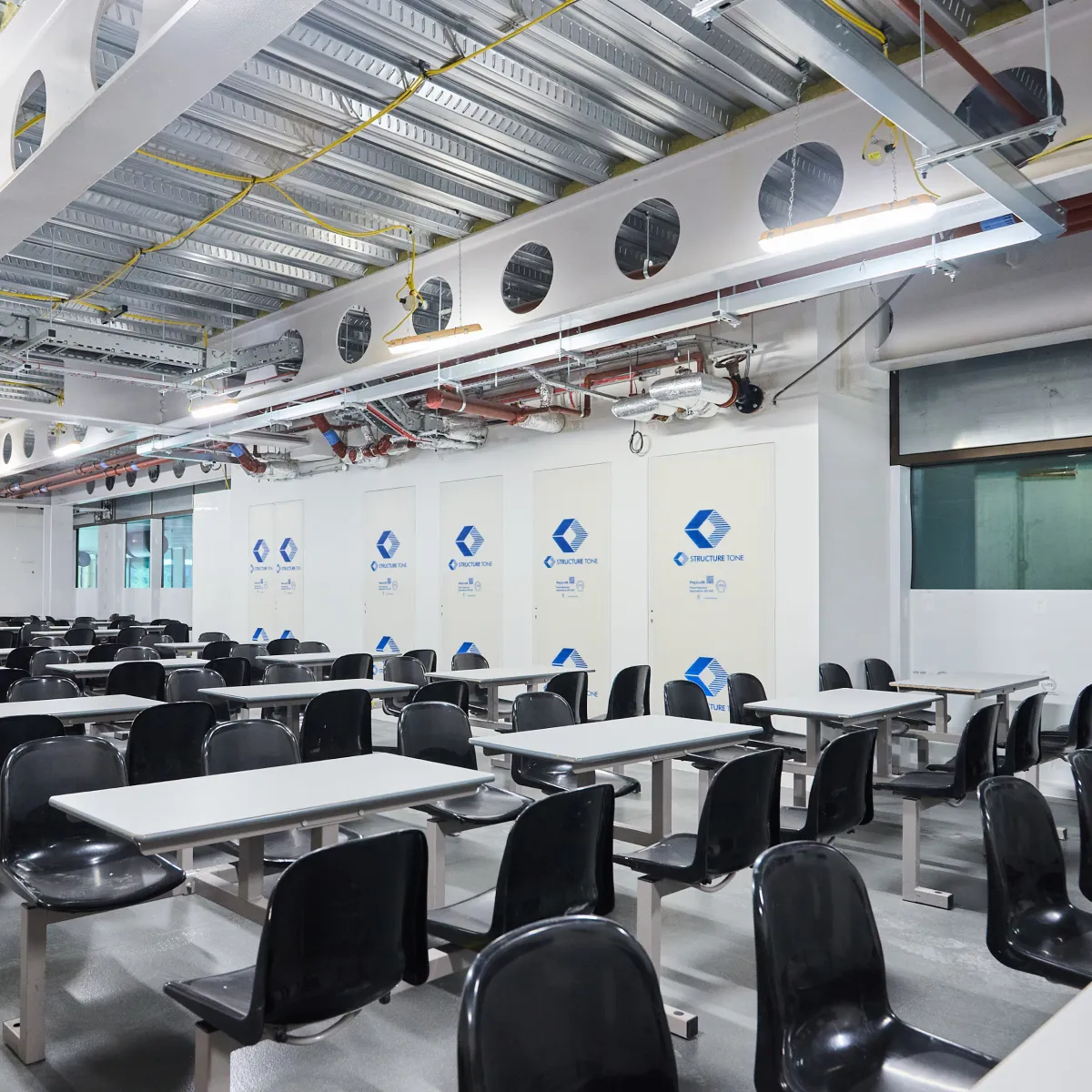 Training room with rows of black chairs and exposed ceiling ductwork.