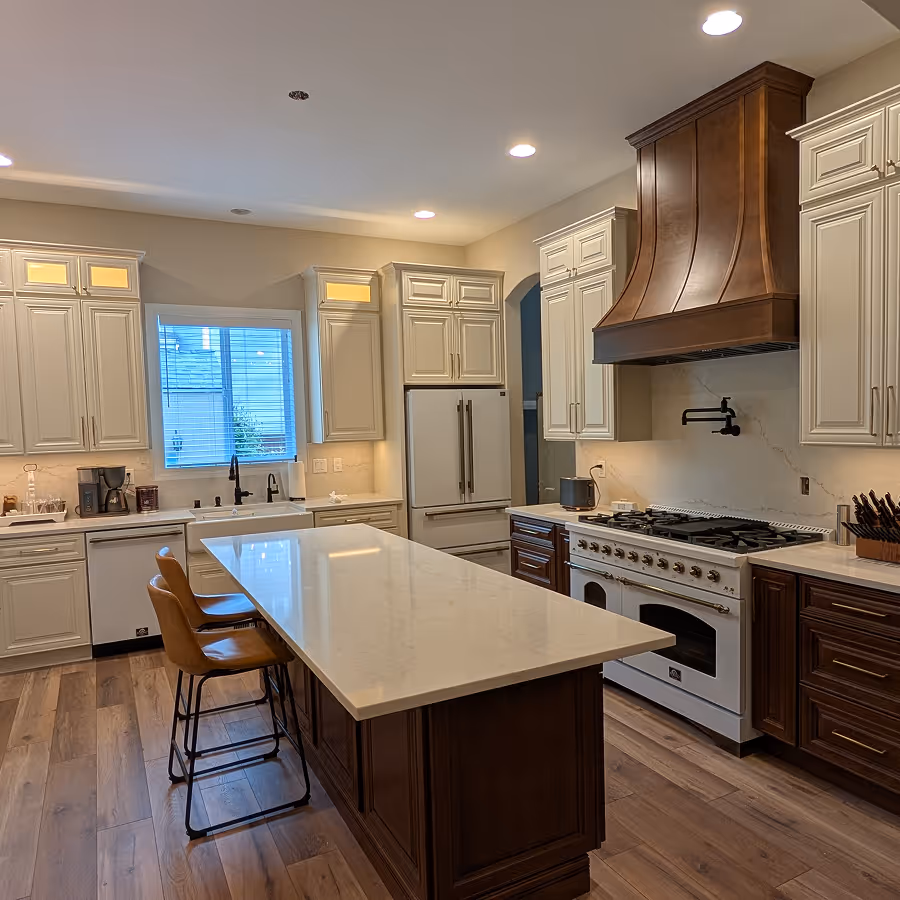 Elegant kitchen with white cabinets, a dark wood island with stools, a matching dark wood range hood, and light wood flooring.