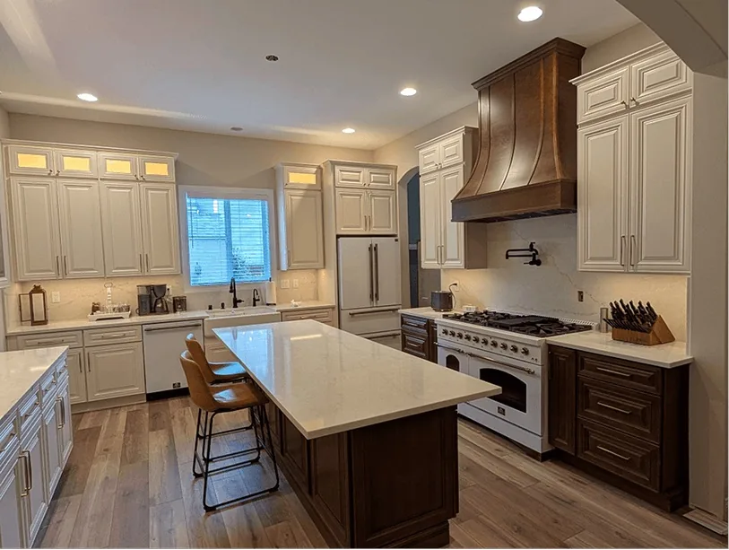 After: the same range wall with a range, a statement hood and painted cabinets