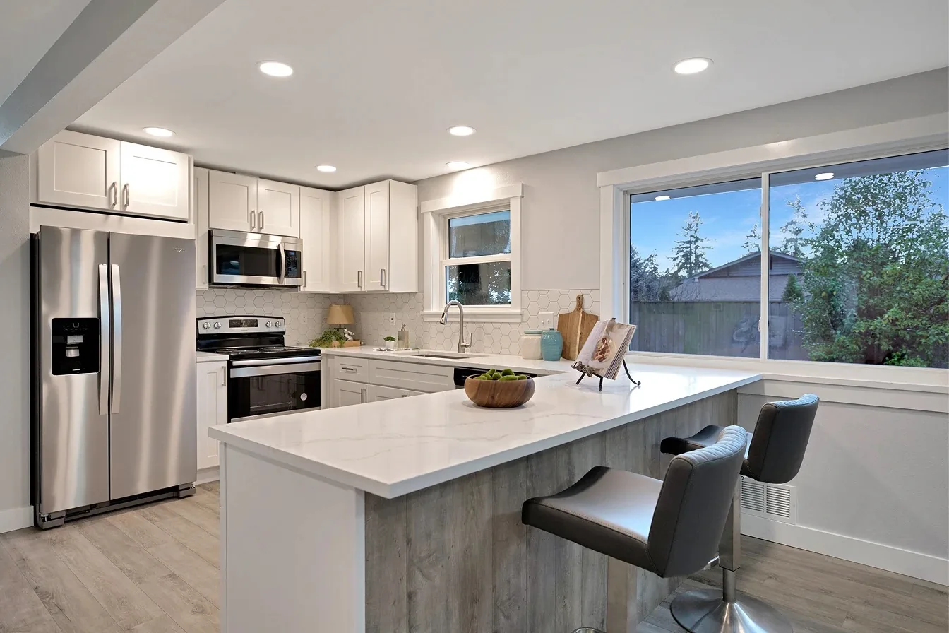 Bright white kitchen with a peninsula, bar seating and a large picture window