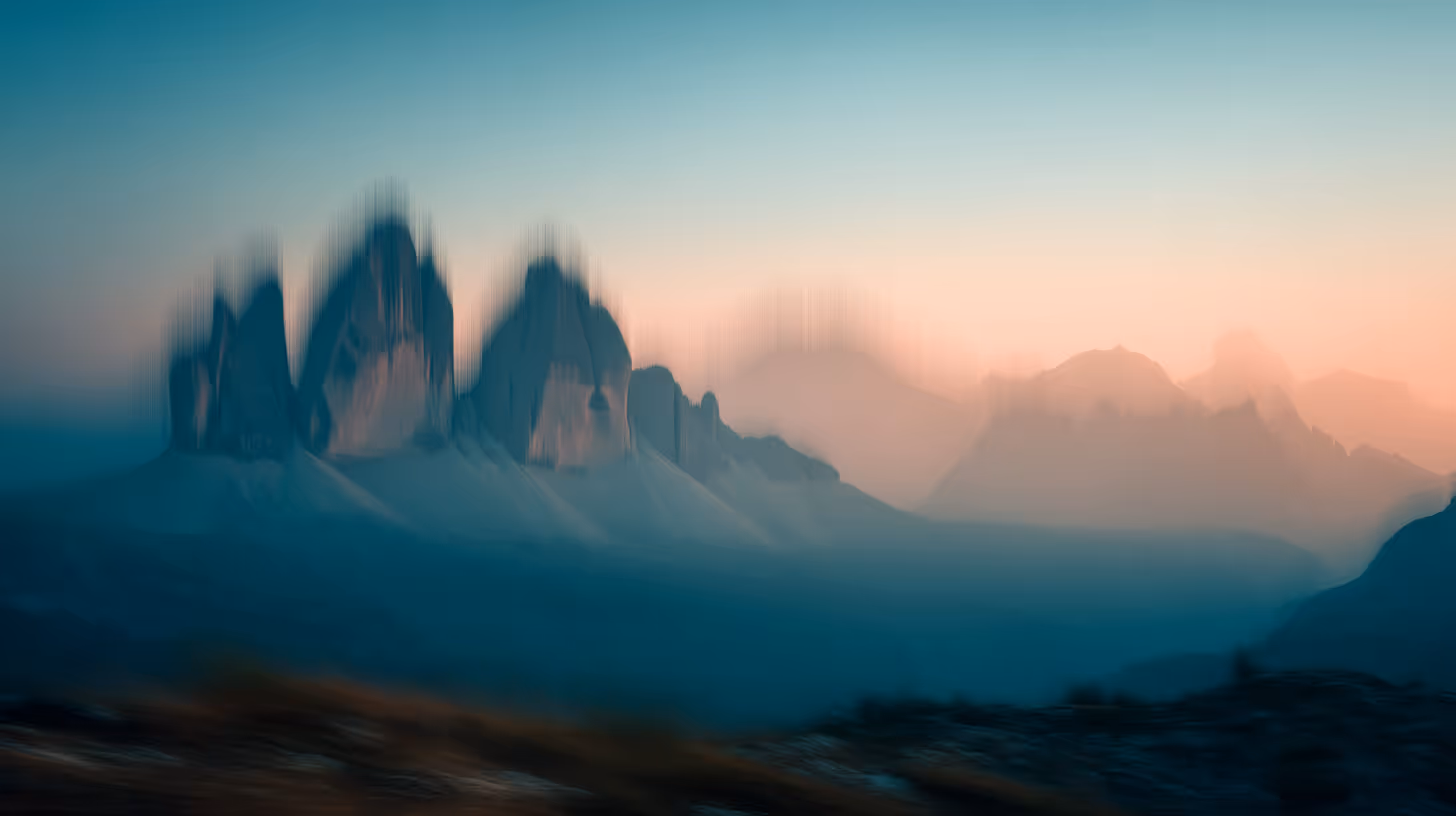 Blurred mountain range at sunrise with pink and blue sky.