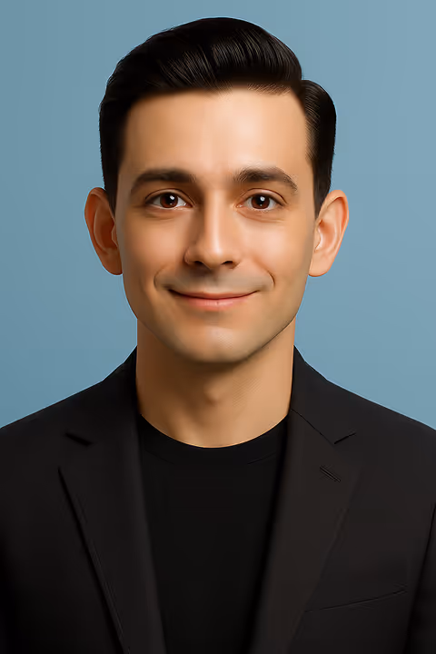 Smiling man with dark hair wearing a black blazer and shirt against a blue background.