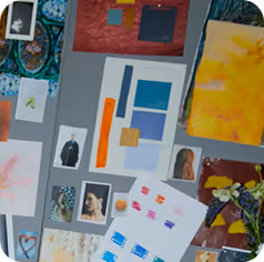 A collage of various artworks, color swatches, photographs, and painted paper arranged on a grey surface.
