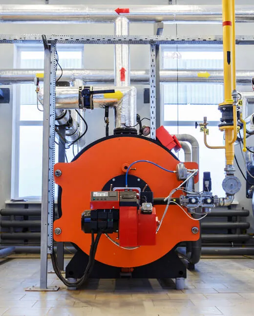 Industrial orange boiler with connected pipes, gauges, and control unit inside a utility room.