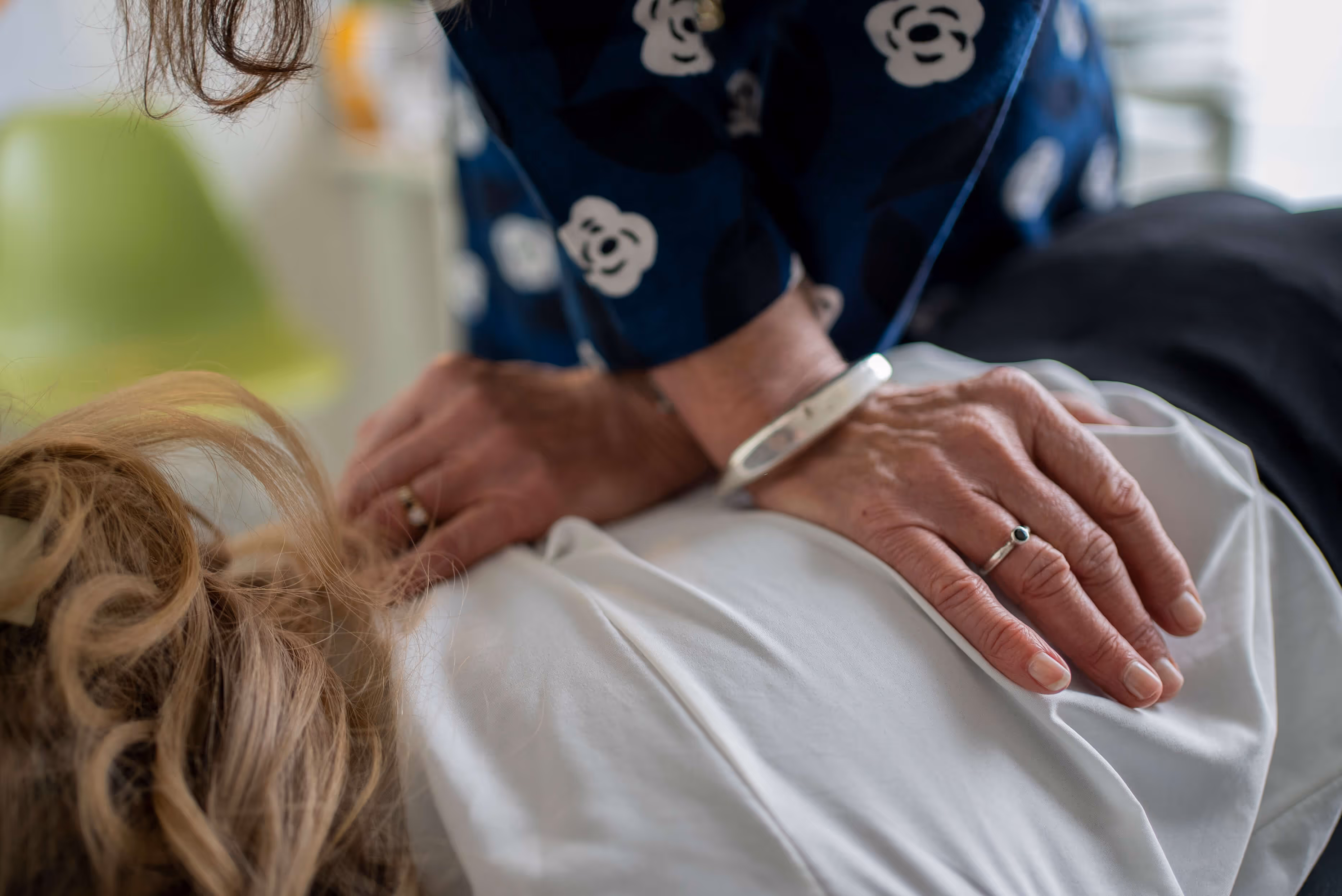 Chiropractor performing a spinal adjustment on a patient lying face down.