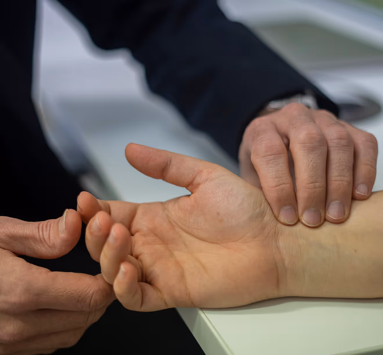Doctor checking patient's wrist pulse with one hand holding the wrist and the other feeling the pulse.