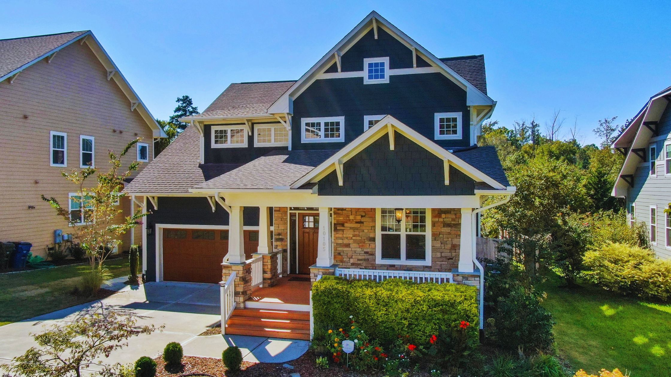 "A modern suburban home with a spacious driveway and double garage, set against a vibrant sunset sky, featuring well-maintained landscaping and a cozy porch light illuminating the entryway.