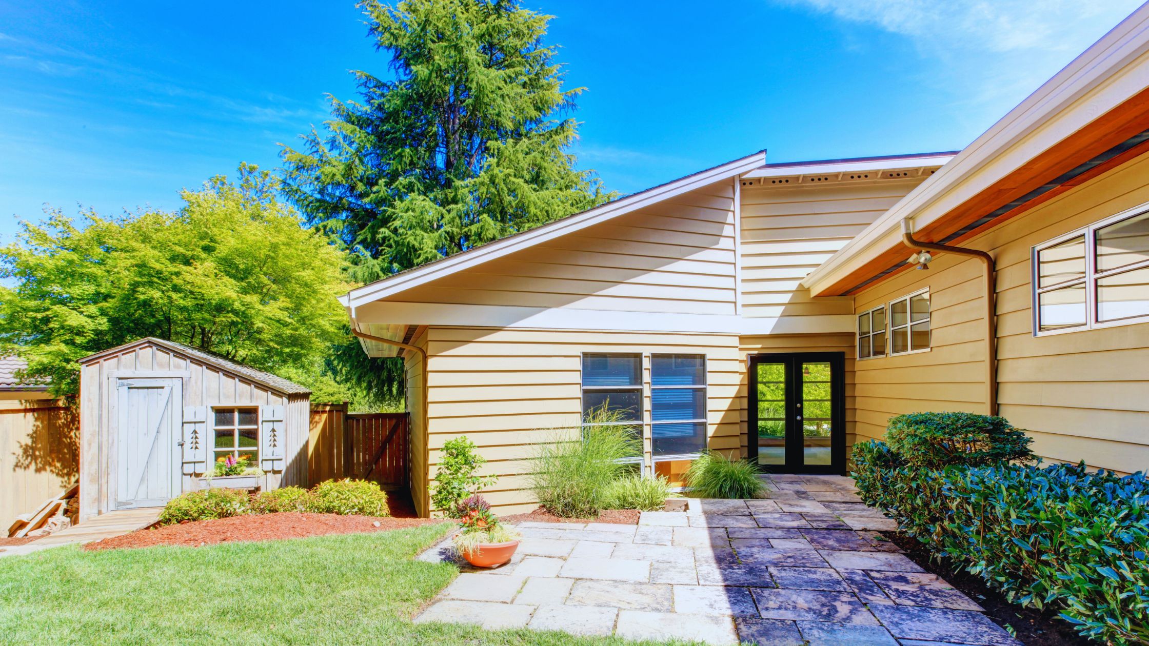 "A modern suburban home with a spacious driveway and double garage, set against a vibrant sunset sky, featuring well-maintained landscaping and a cozy porch light illuminating the entryway.