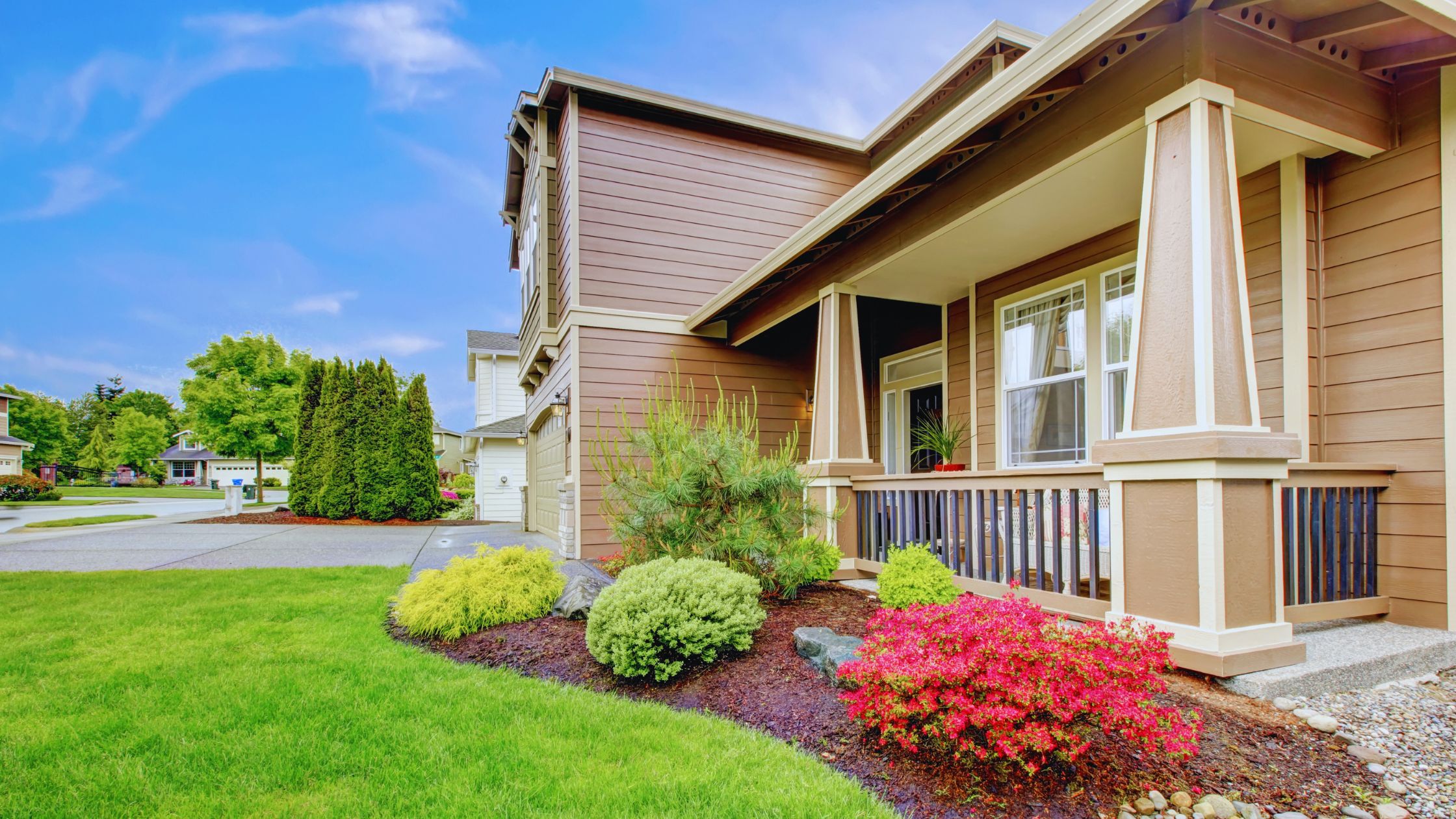 "A modern suburban home with a spacious driveway and double garage, set against a vibrant sunset sky, featuring well-maintained landscaping and a cozy porch light illuminating the entryway.