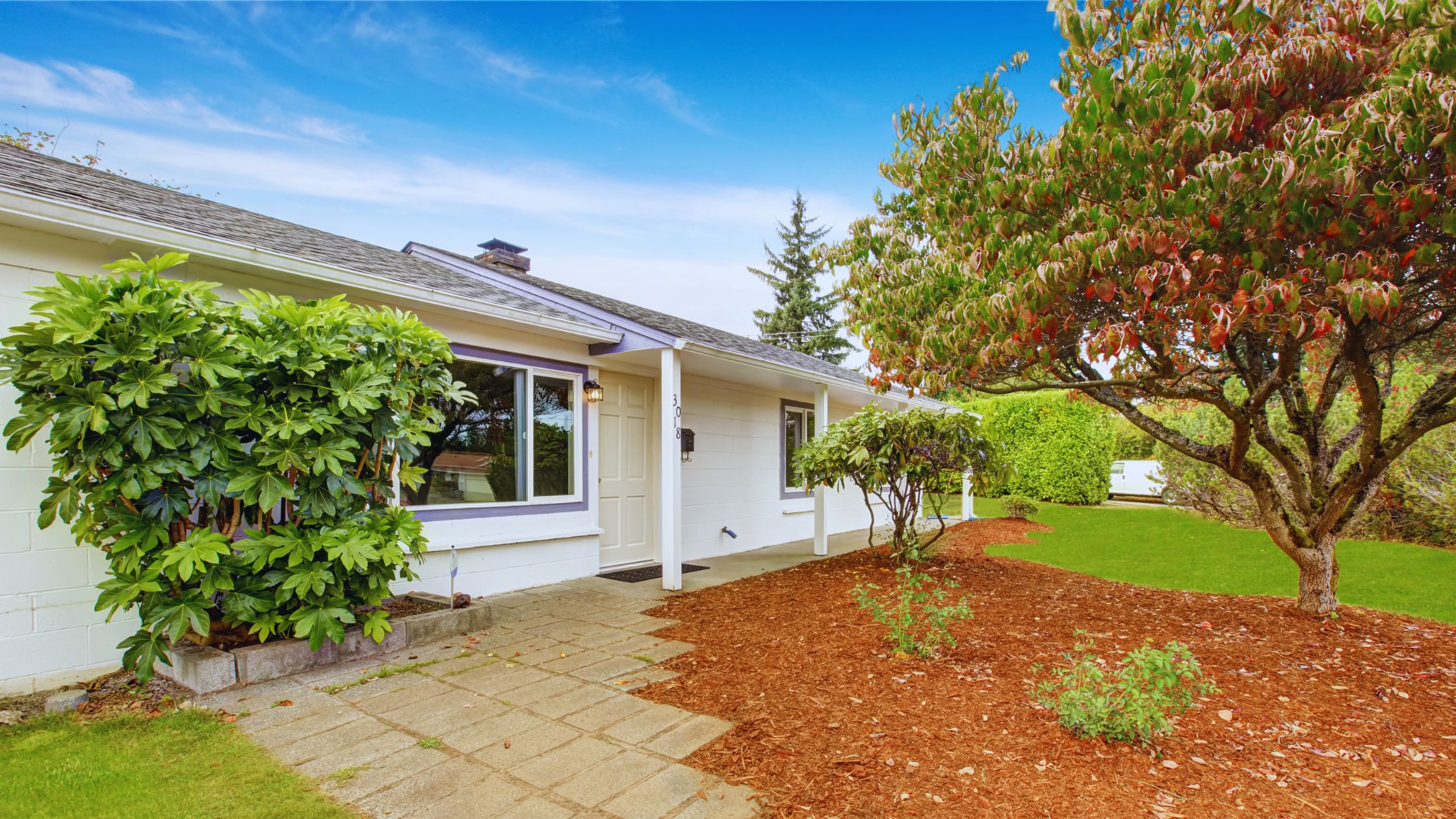 "A modern suburban home with a spacious driveway and double garage, set against a vibrant sunset sky, featuring well-maintained landscaping and a cozy porch light illuminating the entryway.