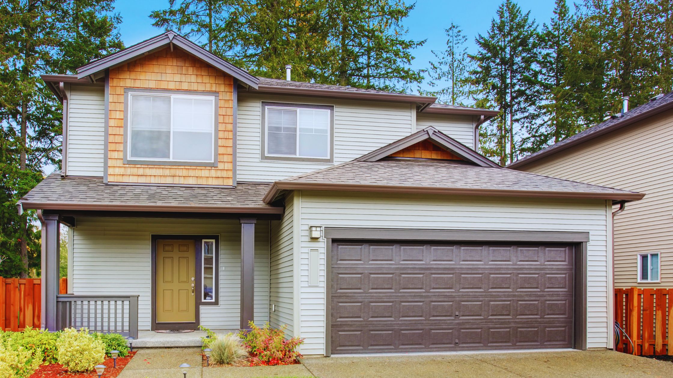 "A modern suburban home with a spacious driveway and double garage, set against a vibrant sunset sky, featuring well-maintained landscaping and a cozy porch light illuminating the entryway.