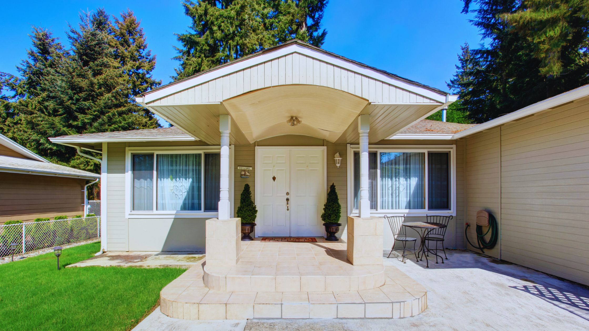 "A modern suburban home with a spacious driveway and double garage, set against a vibrant sunset sky, featuring well-maintained landscaping and a cozy porch light illuminating the entryway.