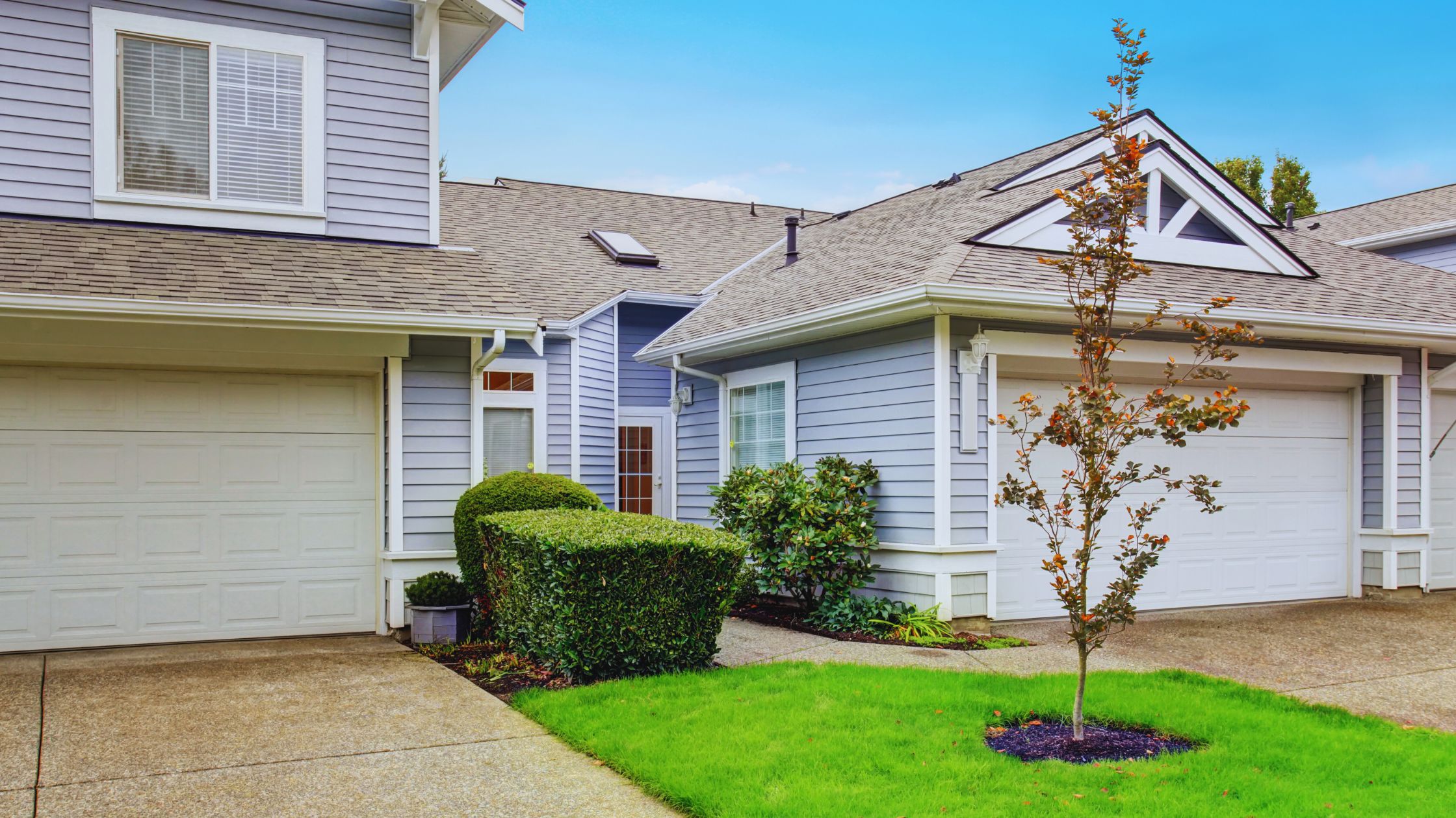 "A modern suburban home with a spacious driveway and double garage, set against a vibrant sunset sky, featuring well-maintained landscaping and a cozy porch light illuminating the entryway.