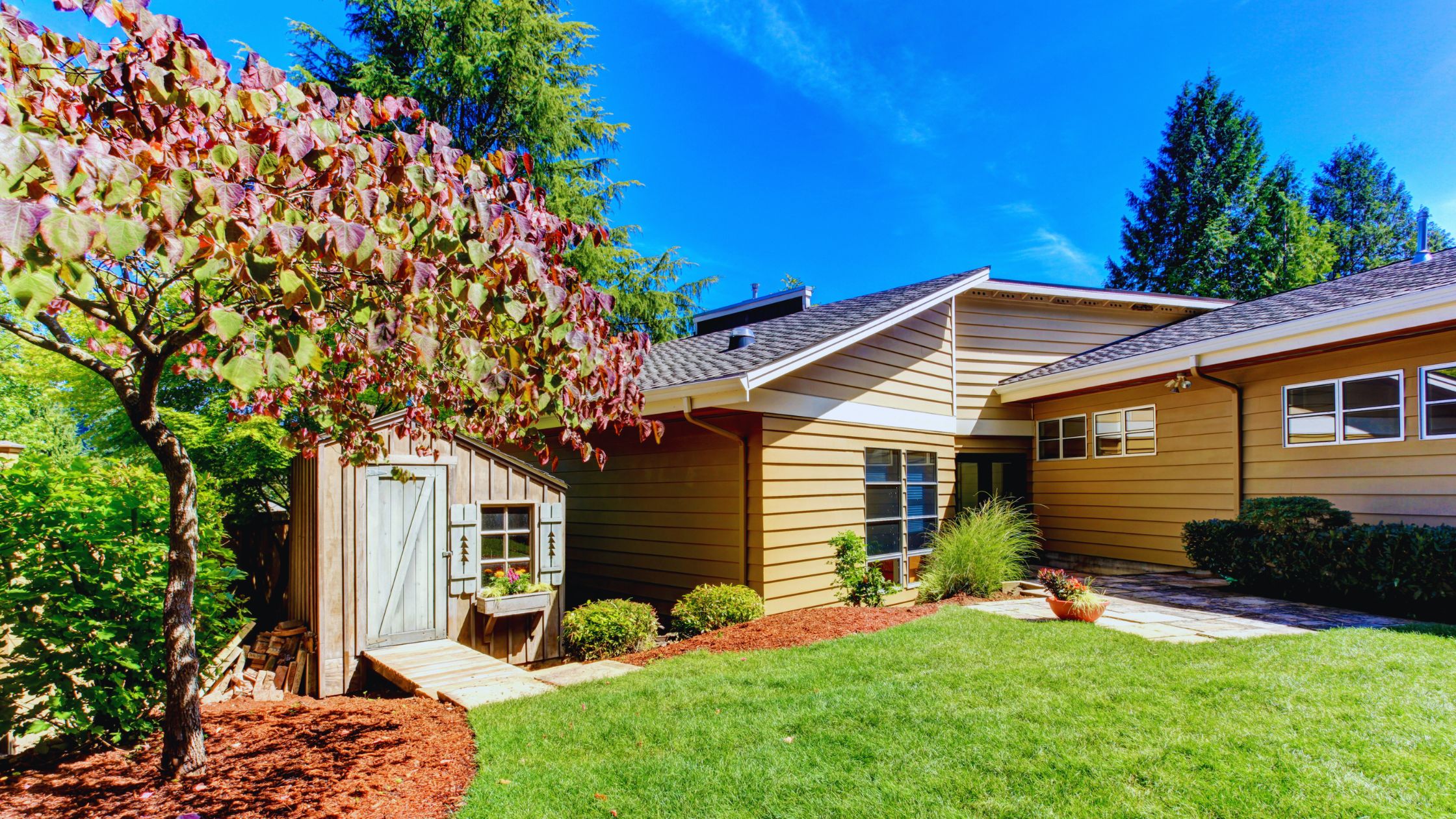 "A modern suburban home with a spacious driveway and double garage, set against a vibrant sunset sky, featuring well-maintained landscaping and a cozy porch light illuminating the entryway.