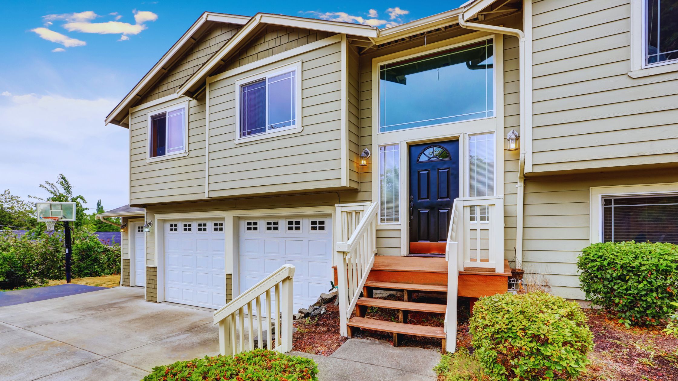 "A modern suburban home with a spacious driveway and double garage, set against a vibrant sunset sky, featuring well-maintained landscaping and a cozy porch light illuminating the entryway.