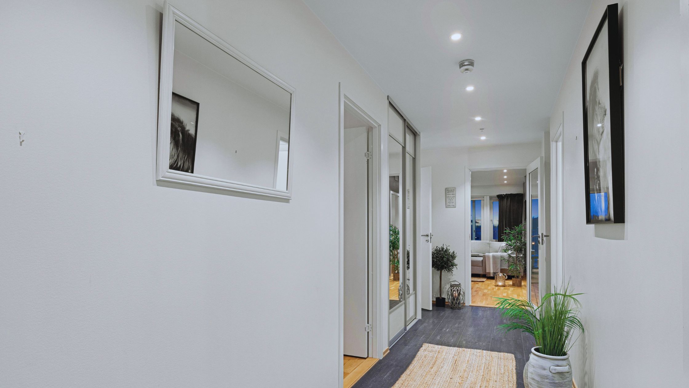 "A modern suburban home with a spacious driveway and double garage, set against a vibrant sunset sky, featuring well-maintained landscaping and a cozy porch light illuminating the entryway.