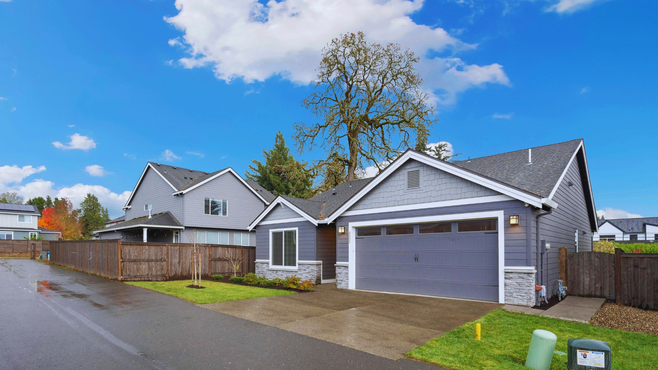 "A modern suburban home with a spacious driveway and double garage, set against a vibrant sunset sky, featuring well-maintained landscaping and a cozy porch light illuminating the entryway.