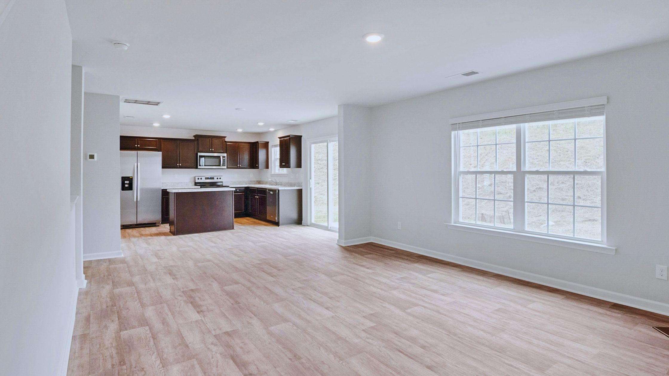 "A modern suburban home with a spacious driveway and double garage, set against a vibrant sunset sky, featuring well-maintained landscaping and a cozy porch light illuminating the entryway.