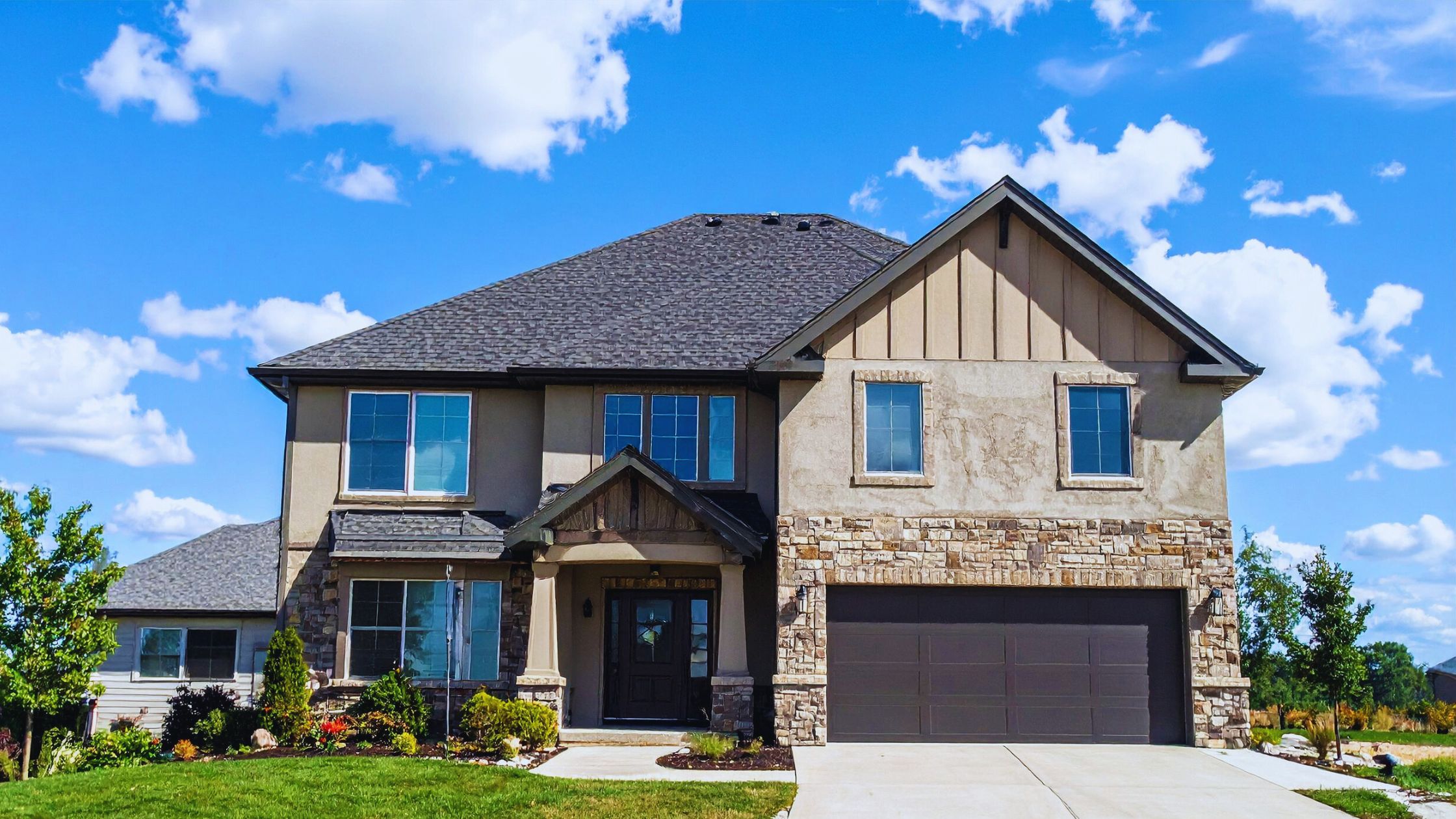 "A modern suburban home with a spacious driveway and double garage, set against a vibrant sunset sky, featuring well-maintained landscaping and a cozy porch light illuminating the entryway.