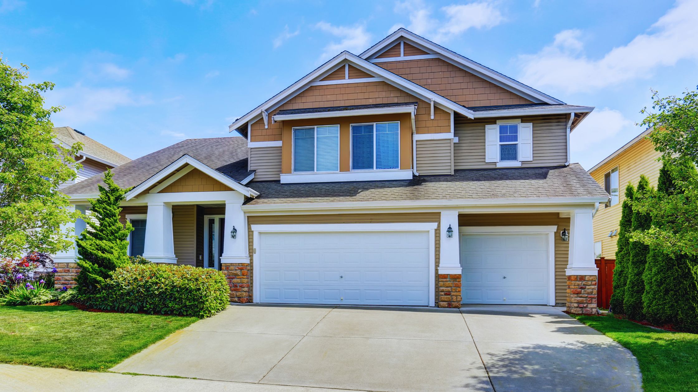 "A modern suburban home with a spacious driveway and double garage, set against a vibrant sunset sky, featuring well-maintained landscaping and a cozy porch light illuminating the entryway.