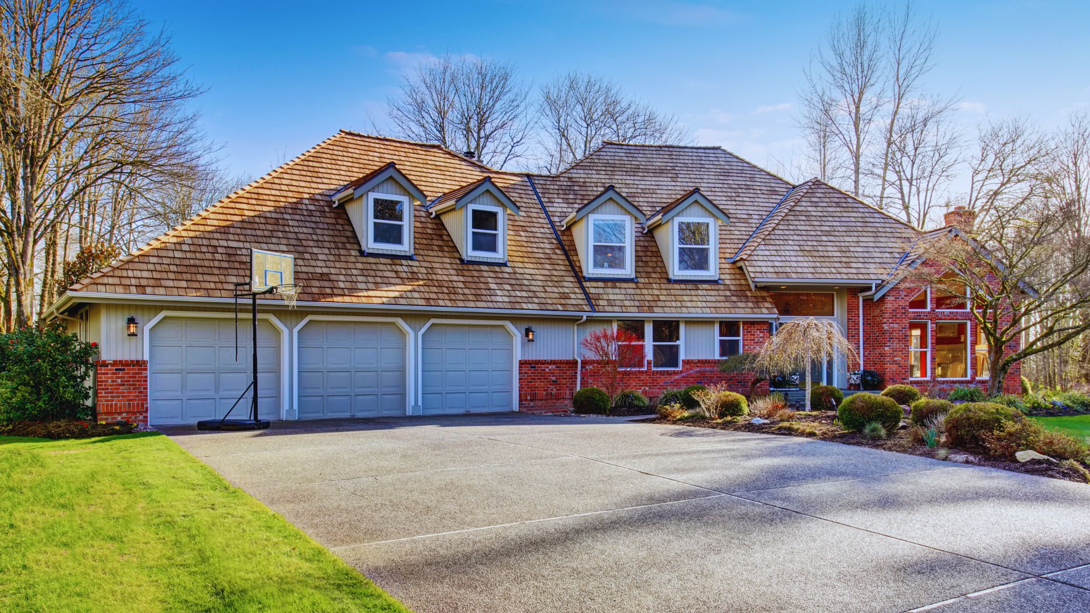 "A modern suburban home with a spacious driveway and double garage, set against a vibrant sunset sky, featuring well-maintained landscaping and a cozy porch light illuminating the entryway.