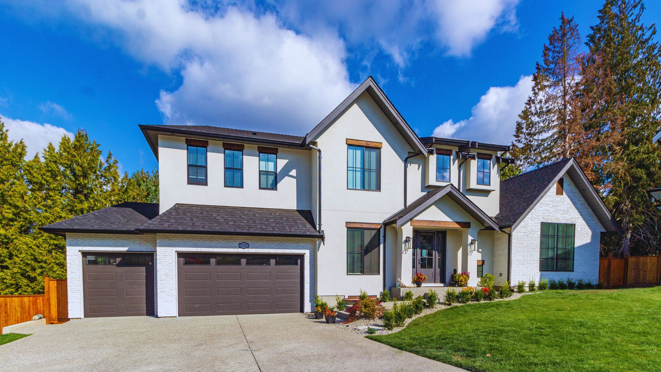 "A modern suburban home with a spacious driveway and double garage, set against a vibrant sunset sky, featuring well-maintained landscaping and a cozy porch light illuminating the entryway.