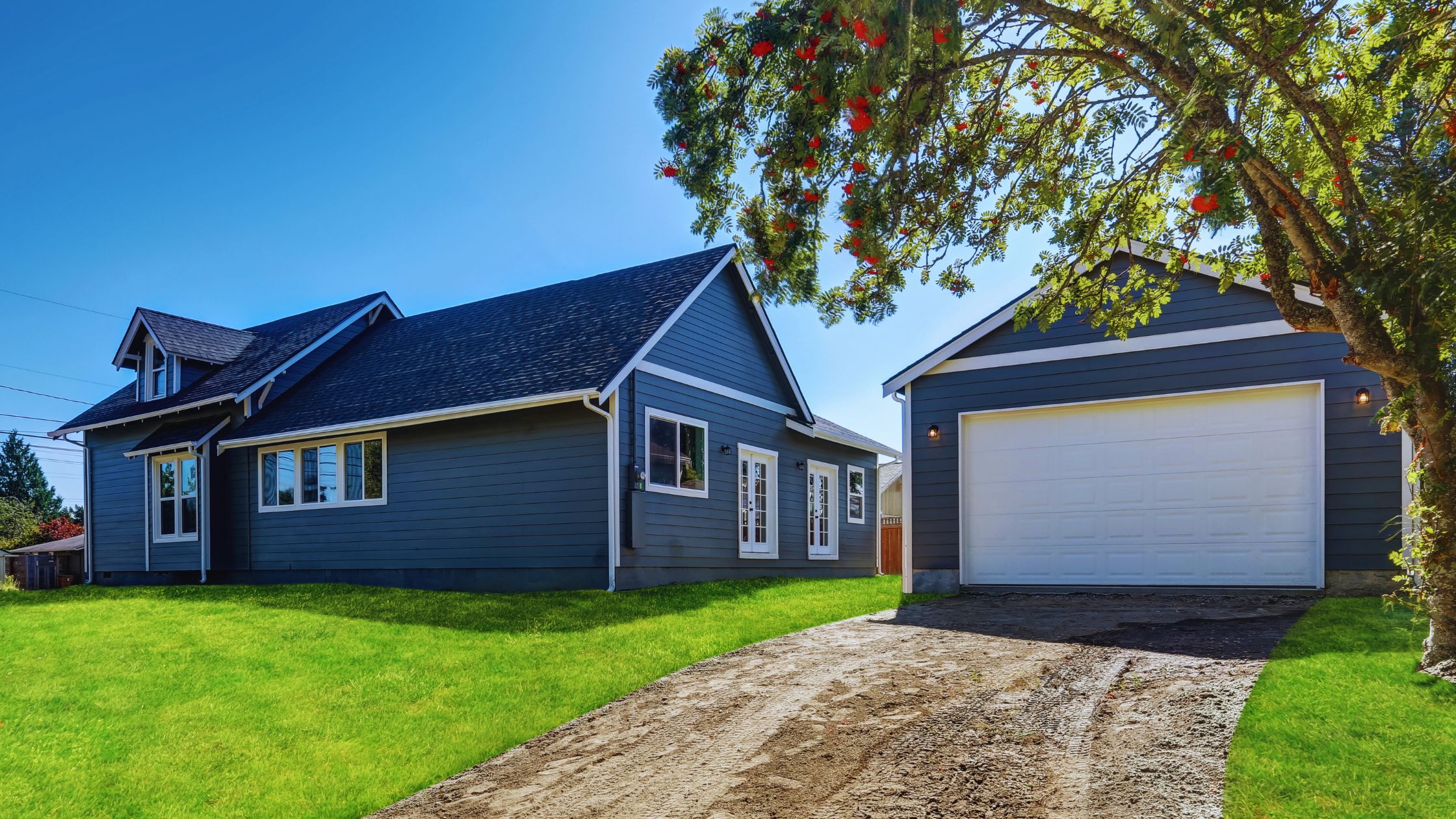 "A modern suburban home with a spacious driveway and double garage, set against a vibrant sunset sky, featuring well-maintained landscaping and a cozy porch light illuminating the entryway.