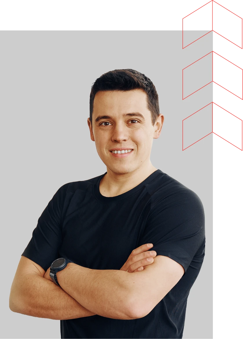 Patrik Korbela, a smiling man with short dark hair, wearing a black athletic t-shirt and a smartwatch, standing with arms crossed against a plain grey background.