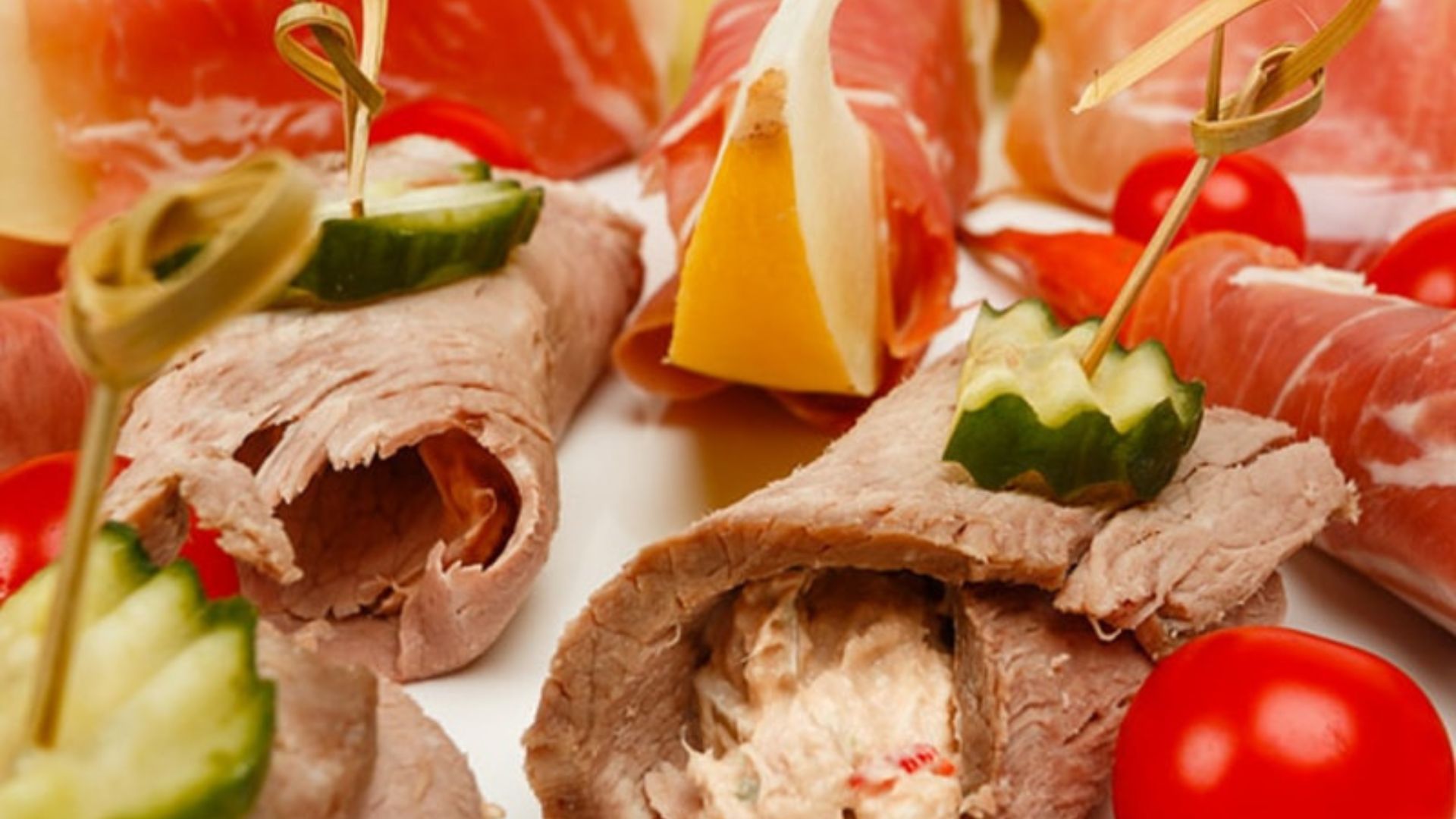 Gefüllte Rinderrouladen mit Gurke, Käse, Schinken und Tomaten als Fingerfood angerichtet
