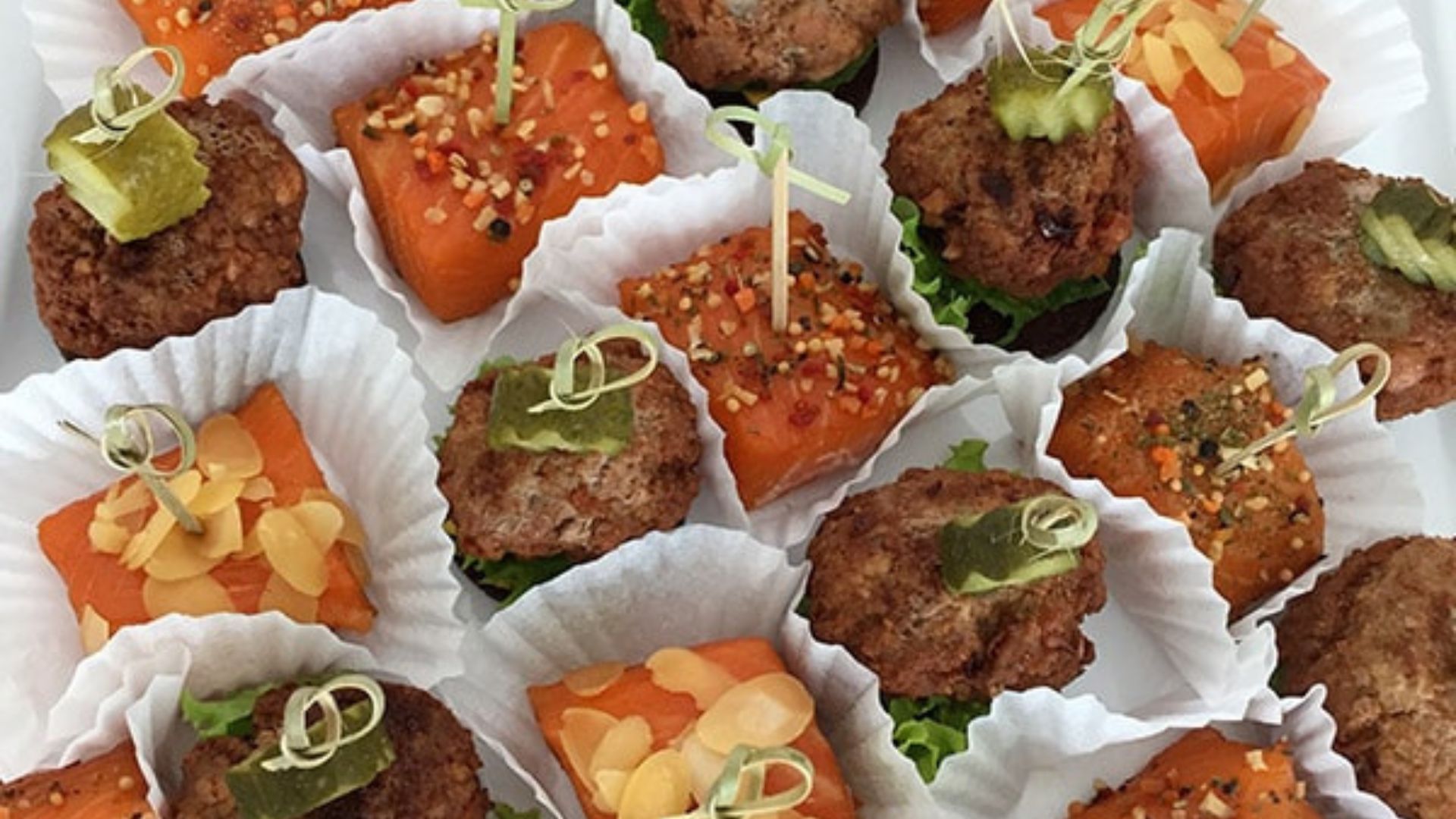 Kleine Fleischbällchen und Lachs-Häppchen als edles Fingerfood angerichtet.