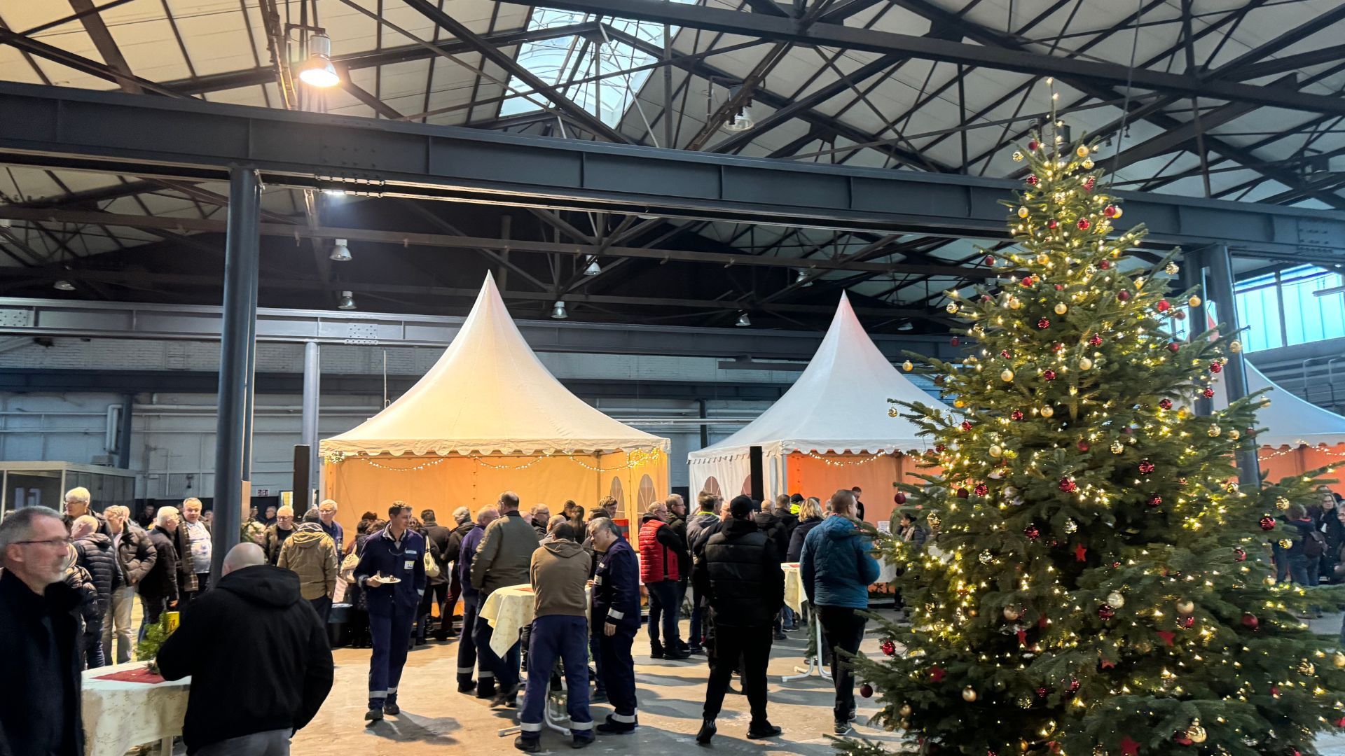 Weihnachtsfeier in großer Halle mit geschmücktem Tannenbaum
