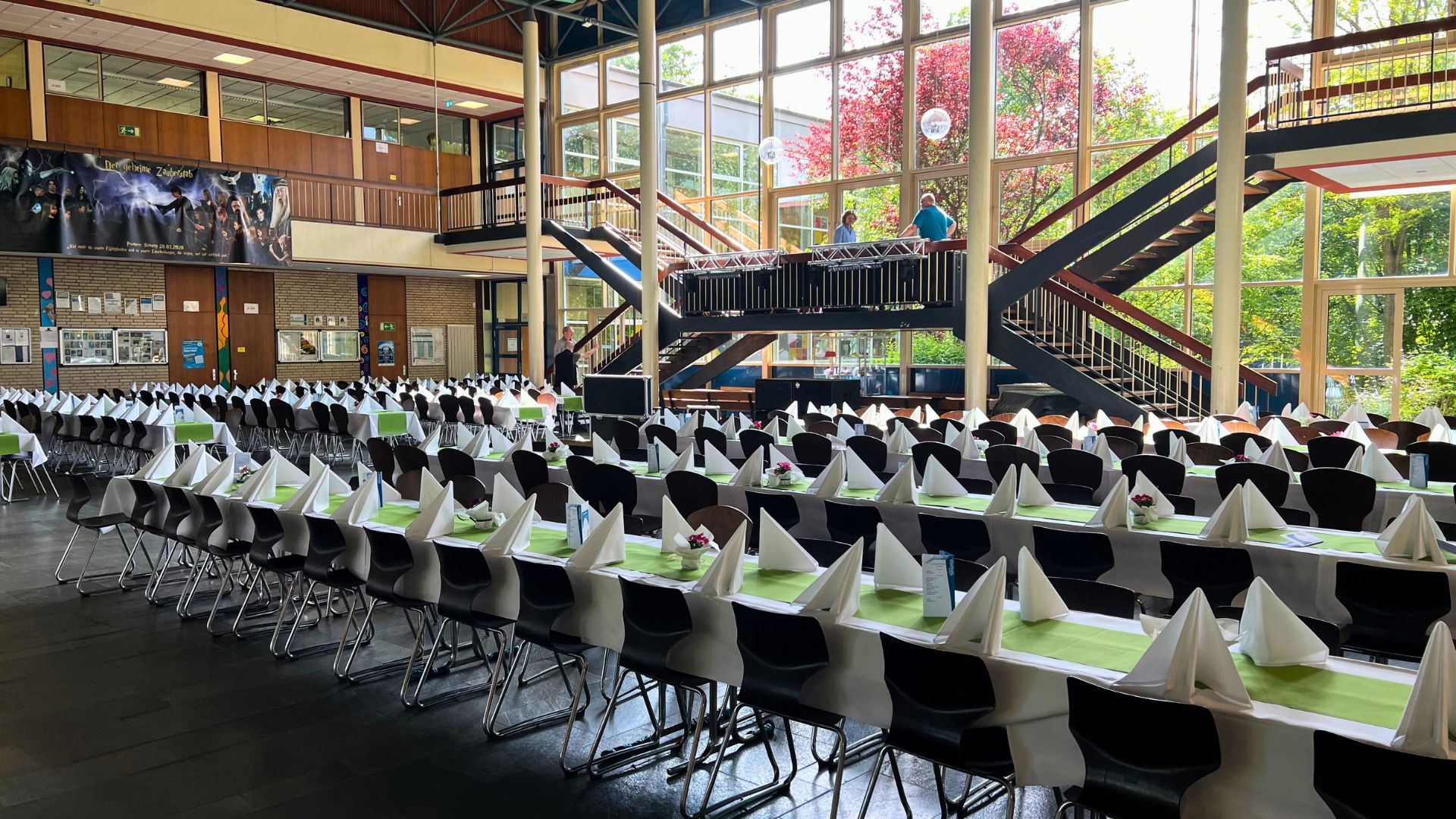 Festlich gedeckter Saal mit langen Tischreihen