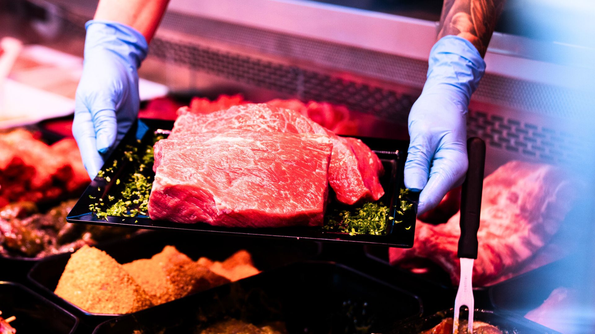 Frisches Stück Fleisch in einer Metzgerei wird auf einem Tablett mit grüner Garnitur präsentiert
