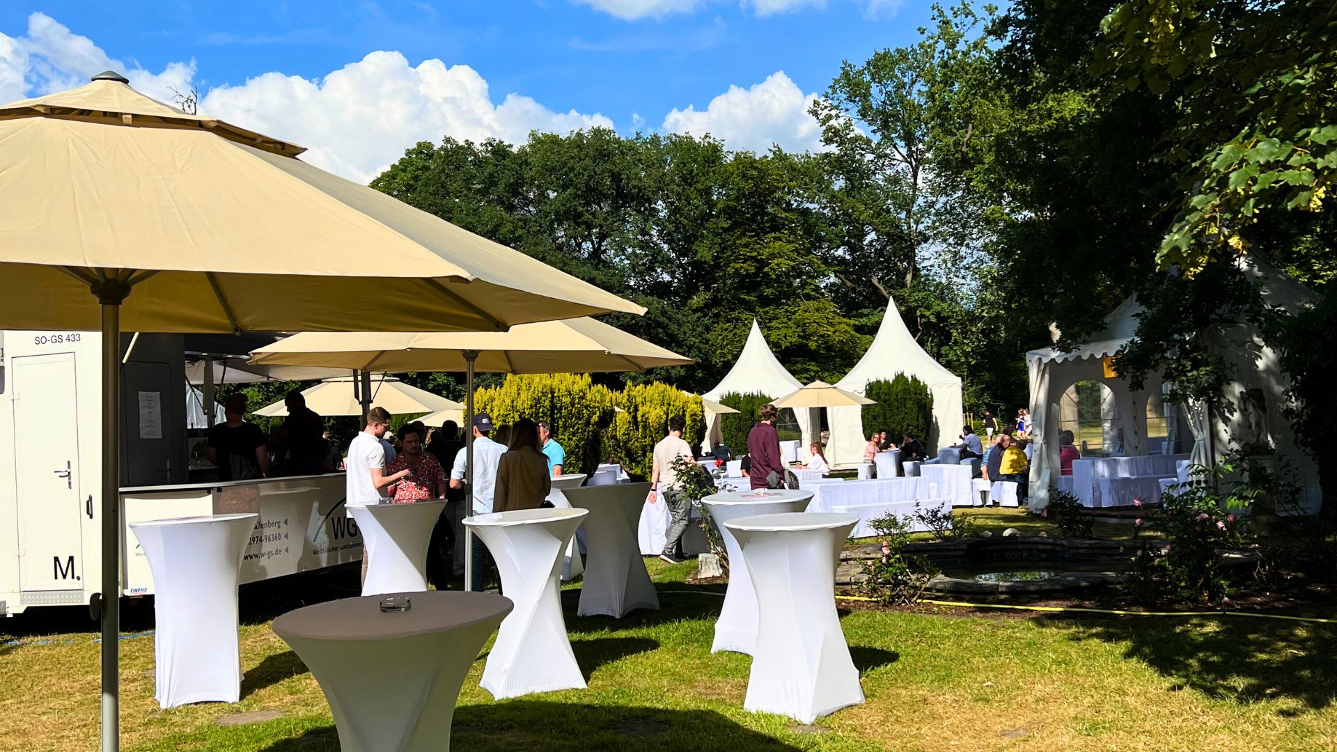 „Sommerliche Firmenfeier im Freien mit Stehtischen, Sonnenschirmen und Pavillons